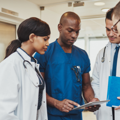 Three doctors and a nurse look at something that the nurse is pointing out on the piece of paper in his hand