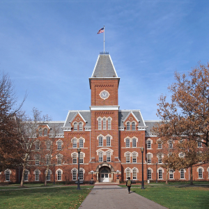 A fancy college or university building with one person with a backpack walking towards it.