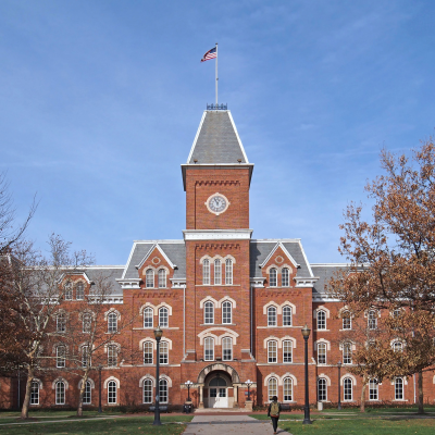 A fancy college or university building with one person with a backpack walking towards it.